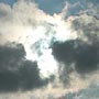 Sunlight burns through the cloud cover to stream across the sky.